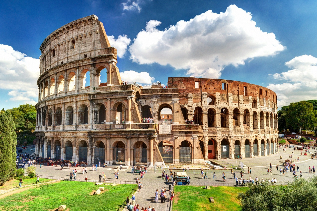 Panoramic view of the Colosseum from the Piazza del Colosseo under a blue summer sky
