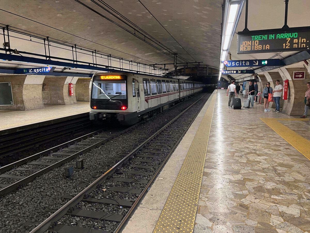 Metro station in Rome with an arriving Line B train and a departure board