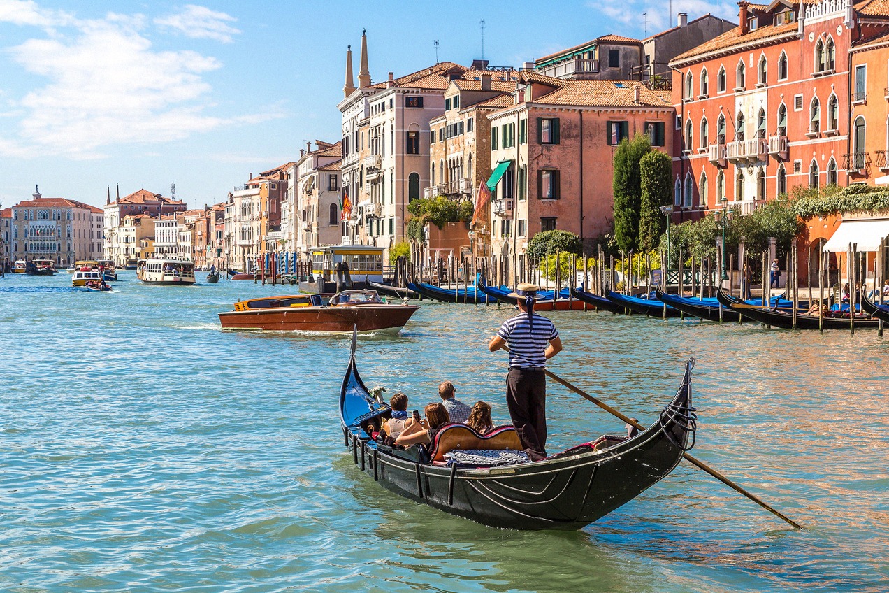 Gondola with tourists on the Grand Canal, colorful palazzo facades in the background